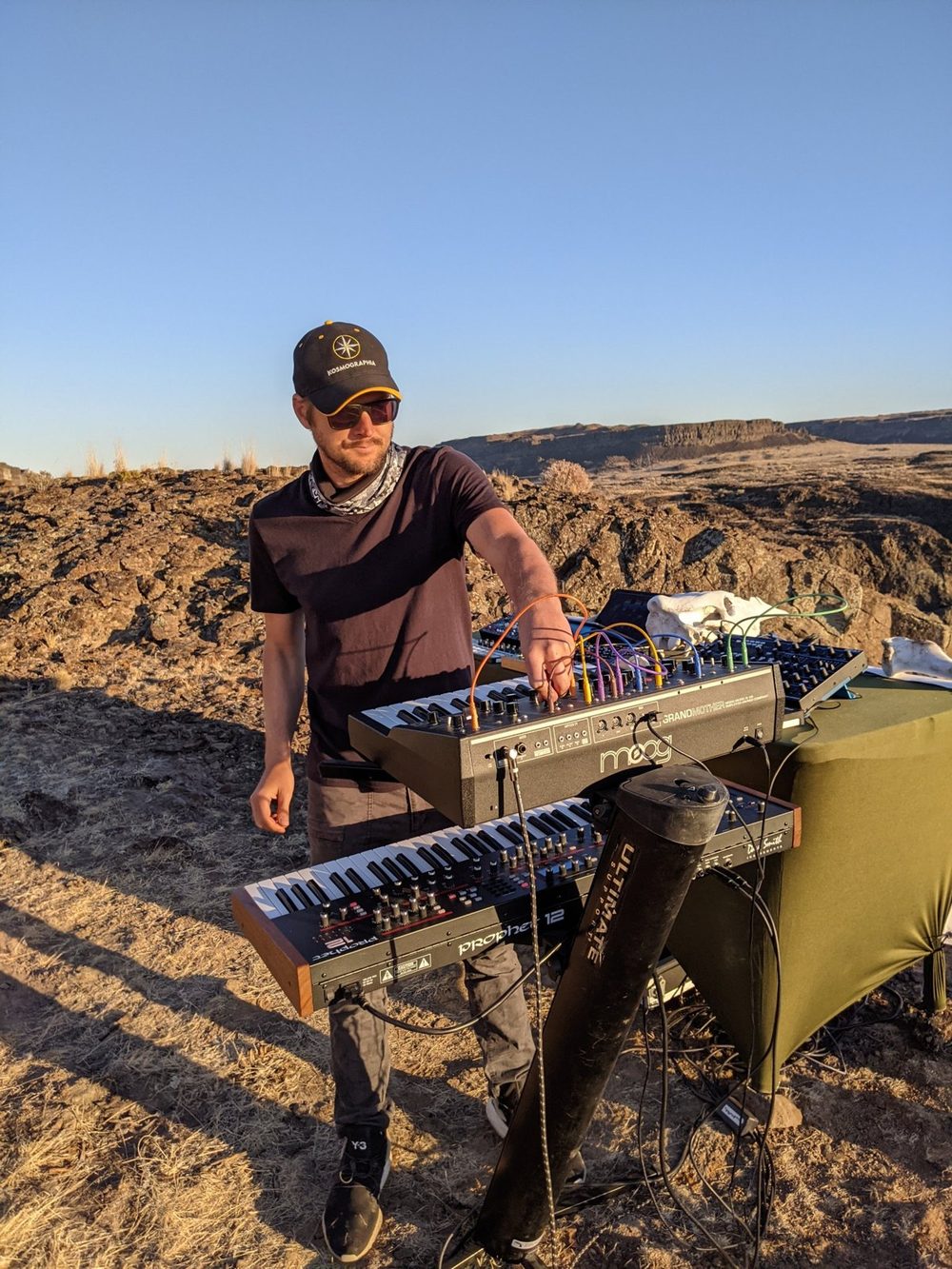 Kevin playing synthesizers outdoors on a desert ridge at golden hour